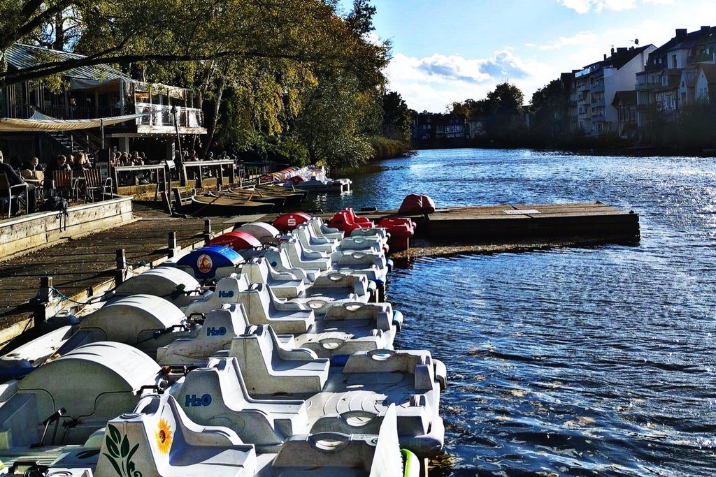 Gelb-rotes Tretboot mit zwei Gästen auf der Lahn bei Sonnenschein