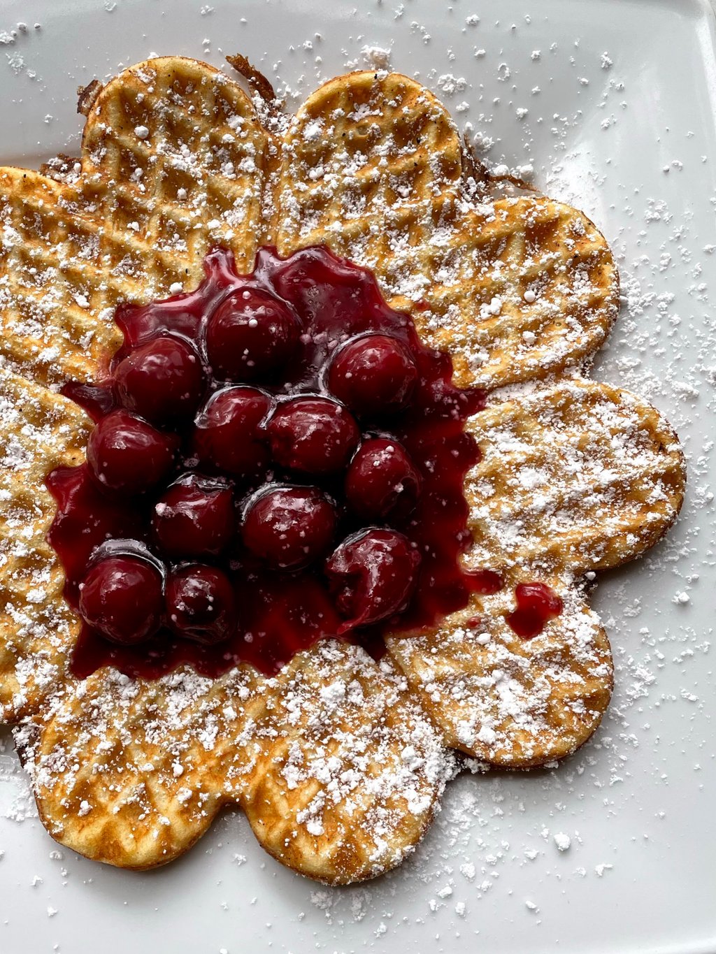 Herzförmige Waffel mit frischen Kirschen und Puderzucker