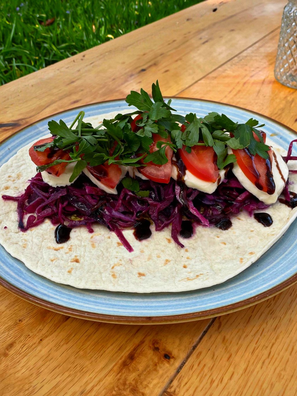 Aufgeklappter Wrap mit Rotkohl, Tomate-Mozzarella und Balsamico-Dressing im Freien