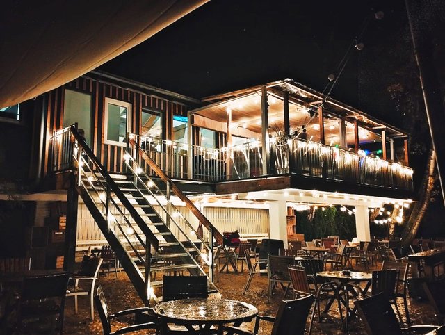 Bootshaus am Abend mit Lichterketten und nassen Reflexionen auf der Terrasse