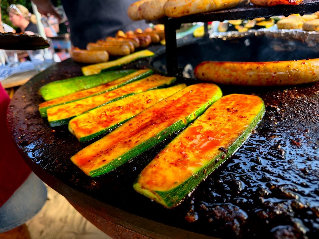 Gegrillte Zucchinischeiben und Bratwürste auf der Plancha-Grillplatte