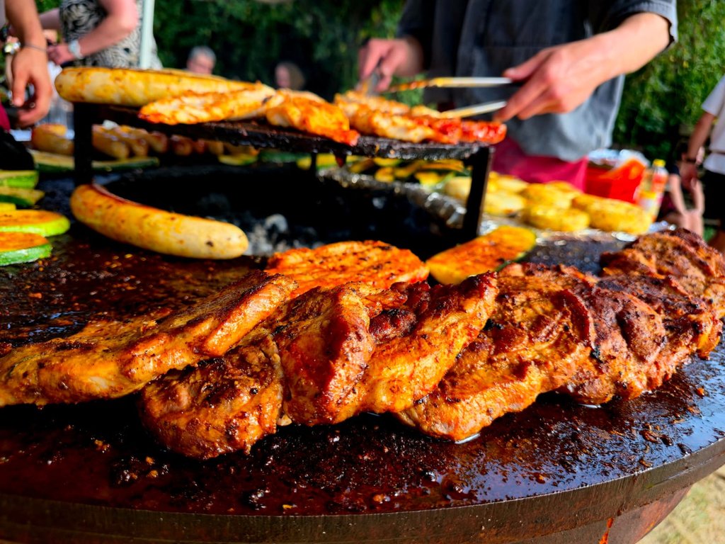 Grillmeister serviert Fleisch und Grillgemüse an die Gäste einer Feier